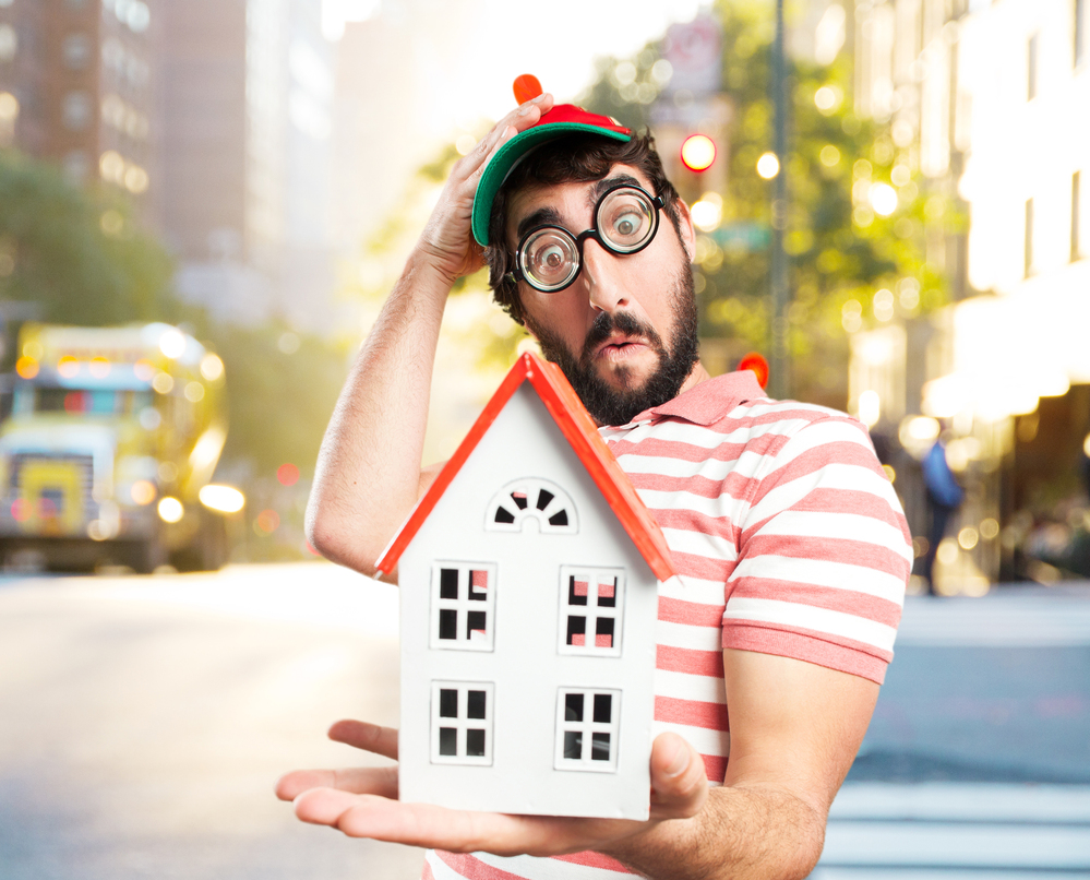 Homme surpris tenant une maquette de maison, illustrant une vente immobilière à Dijon