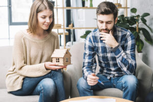 Jeune couple envisageant d’acheter une maison à La Réunion, tenant une maquette de maison.